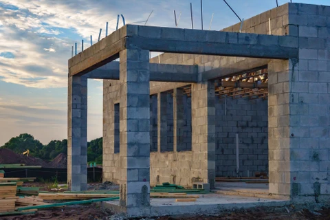 Chantier extérieur de maçonnerie avec ouvrier posant des briques rouges