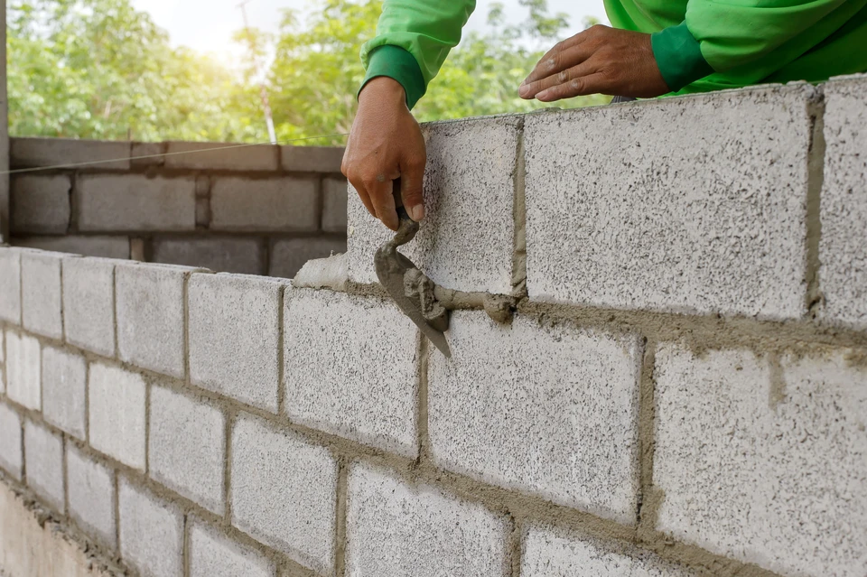 Trois professionnels de la construction en tenue de sécurité se serrant la main sur un chantier, symbolisant le travail d'équipe et la collaboration